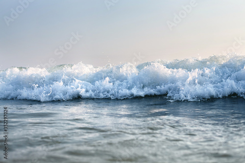 sea wave with splashes surges to the beach, against the sky