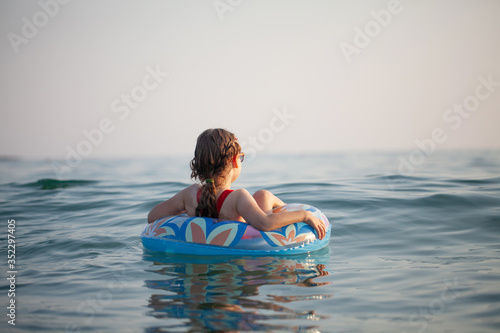Photography young girl in glasses swims in the water on an inflatable donut in the hot sunny