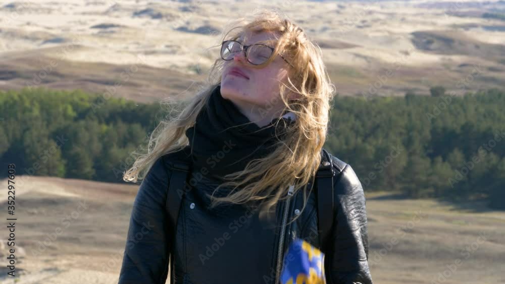 Young woman takes a deep breath surrounded by dunes . Female with glasses takes off her face mask. Gentle moment. Young woman takes a deep breath surrounded by dunes . Female with glasses takes off her face mask. Gentle moment.