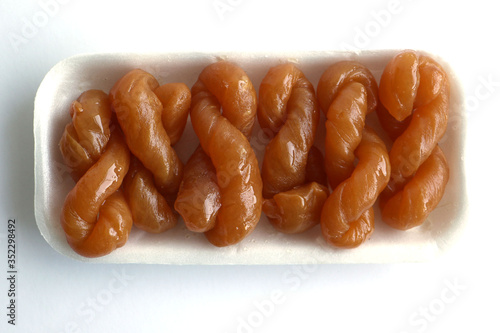 Traditional South African sweet koeksisters covered in syrup, isolated in a polystyrene tray on white background