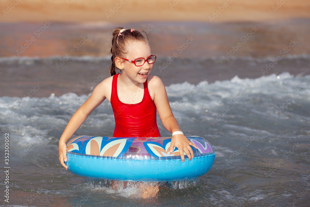 Obraz premium young girl in glasses plays in the water on an inflatable donut in a hot sunny summer