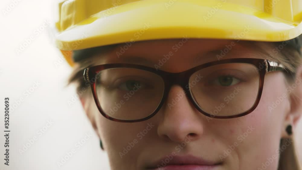 Close up. Young woman, engineer with yellow hard hat . Portrait, slow motion with shallow depth of field. Close up. Young woman, engineer with yellow hard hat . Portrait, slow motion with shallow depth of field.