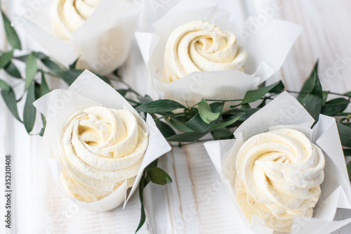 yellow marshmallows on a wooden background decorated with greens