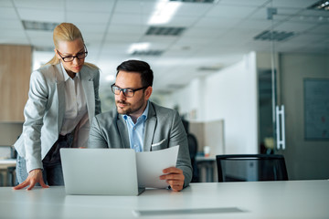 Two serious business people looking at work report or business plan, portrait.