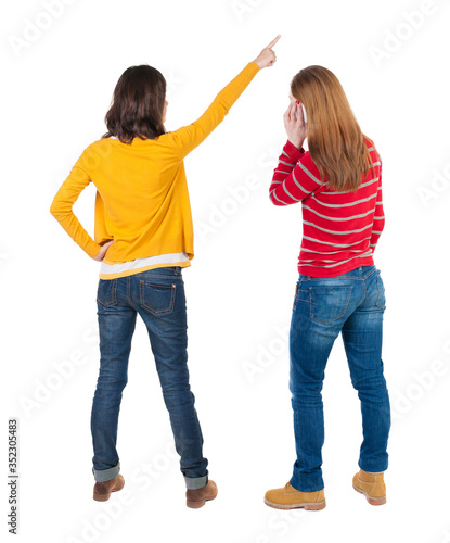 Back view of two young woman photographed on a mobile phone in sweater.
