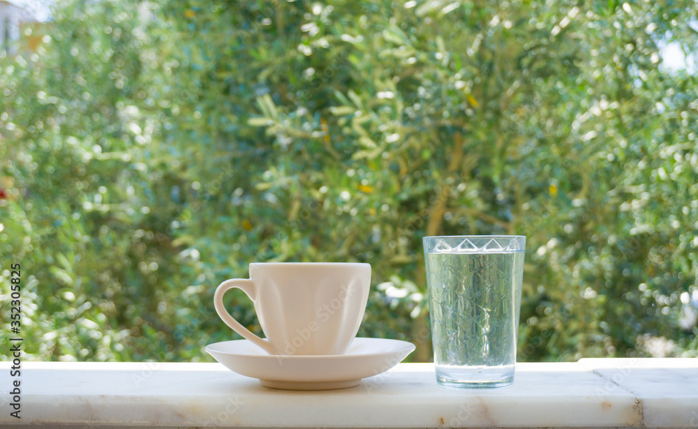 Turkish Coffee with water on nature background. Low view composition. Closeup shot of hot Greek Coffee. Beautiful delicious tasty traditional brown drink of Turkish culture. Enjoy concept photo Turkish Coffee with water on nature background. Low view composition. Closeup shot of hot Greek Coffee. Beautiful delicious tasty traditional brown drink of Turkish culture. Enjoy concept photo