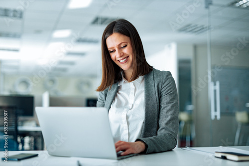Portrait of smiling brunette businesswoman working on laptop in the office.