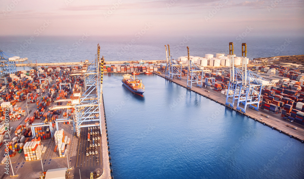 Fototapeta premium Container ship leaving port, export and import business and logistics. Aerial top view sunset