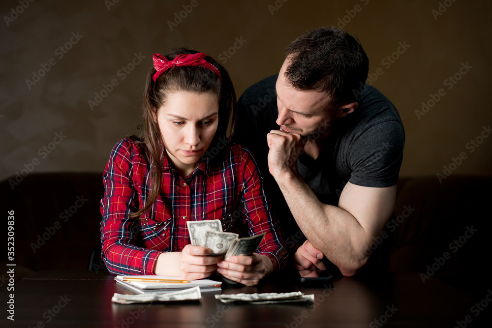 A woman counts family money, a man stands next to her A woman counts family money, a man stands next to her