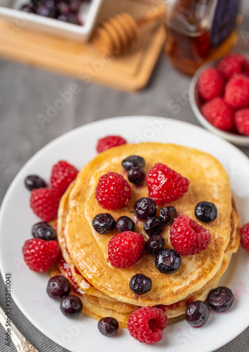 Sweet homemade pancakes with fruits on white plate.