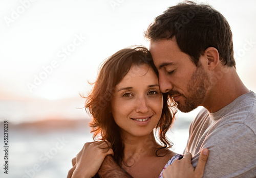 Smiling young woman standing in her husband's arms on a beach