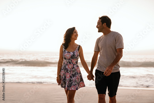 Young couple holding hands and walking along a sandy beach