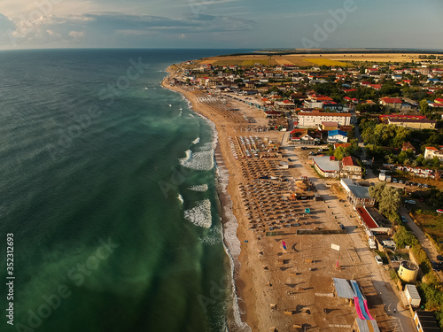 Aerial view of amazing beach with umbrellas and turquoise sea at sunrise. Black Sea at Vama Veche, Romania photo