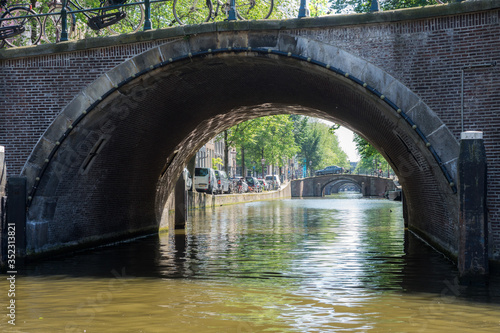look through 7 arc bridges over water of a canal in Amsterdam. Arcs in perspective shot from a boat.