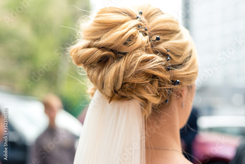 Hairstyle of the bride with blond hair, rear view. Horizontal frame