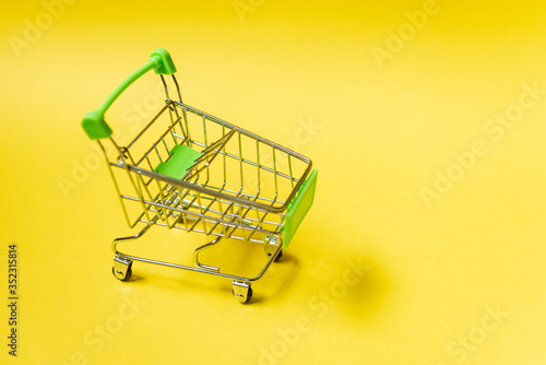 Shopping cart on yellow background. Online commerce concept.