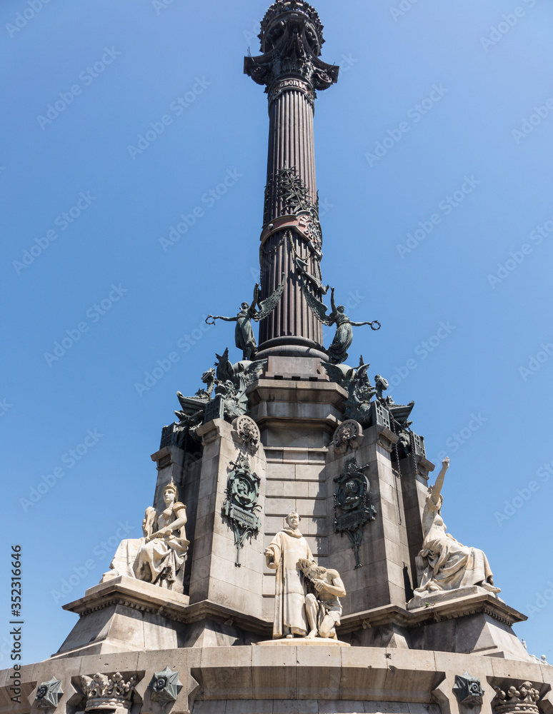 Columbus Monument at the end of La Rambla street near the port in Barcelona. On side of the monument in the sunlight with multiple statiues of people on it