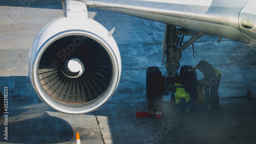Ground service crew repairing and preparing airplane for flight in airport