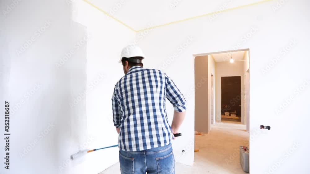 painter manually rolling the grey paint on the wall, apartment renovation painter manually rolling the grey paint on the wall, apartment renovation