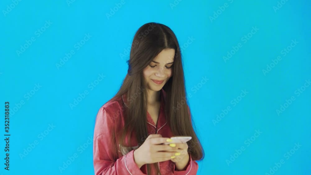Young woman wearing pink pajamas using mobile phone Young woman wearing pink pajamas using mobile phone