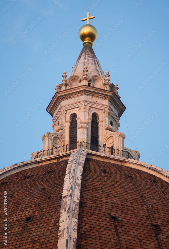 Exterior / facade of the Cathedral of Santa Maria del Fiore in Florence, Italy. Closer look onto a part of the dome with cupola's peak and a cross
