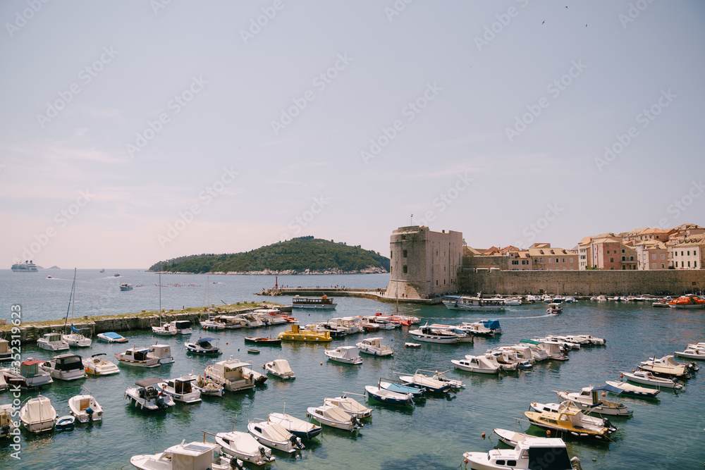 The old port harbor is porporela, near the walls of the old town of Dubrovnik, Croatia. Moored boats and yachts near the city.