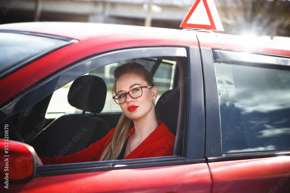 Young beautiful happy woman in red sitting at the wheel new training car. Young beautiful happy woman in red sitting at the wheel new training car.