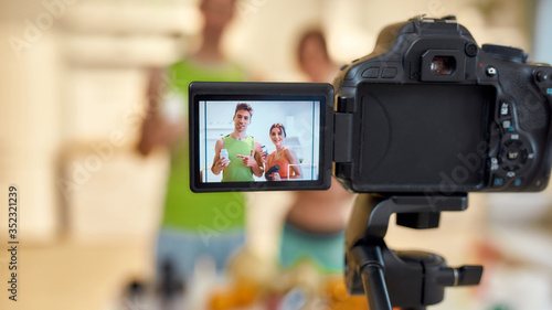 Excellence in every take. Young couple recording video blog or vlog about their nutrition on camera at home. Man and woman showing vitamins and supplements standing in the kitchen