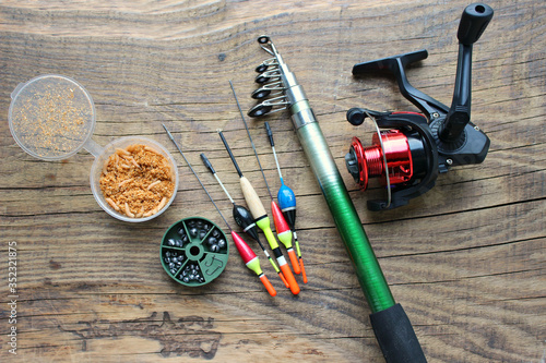 Fishing rods and reels with fishing line on an old wooden background with free space. Floats and other accessories for fishing.