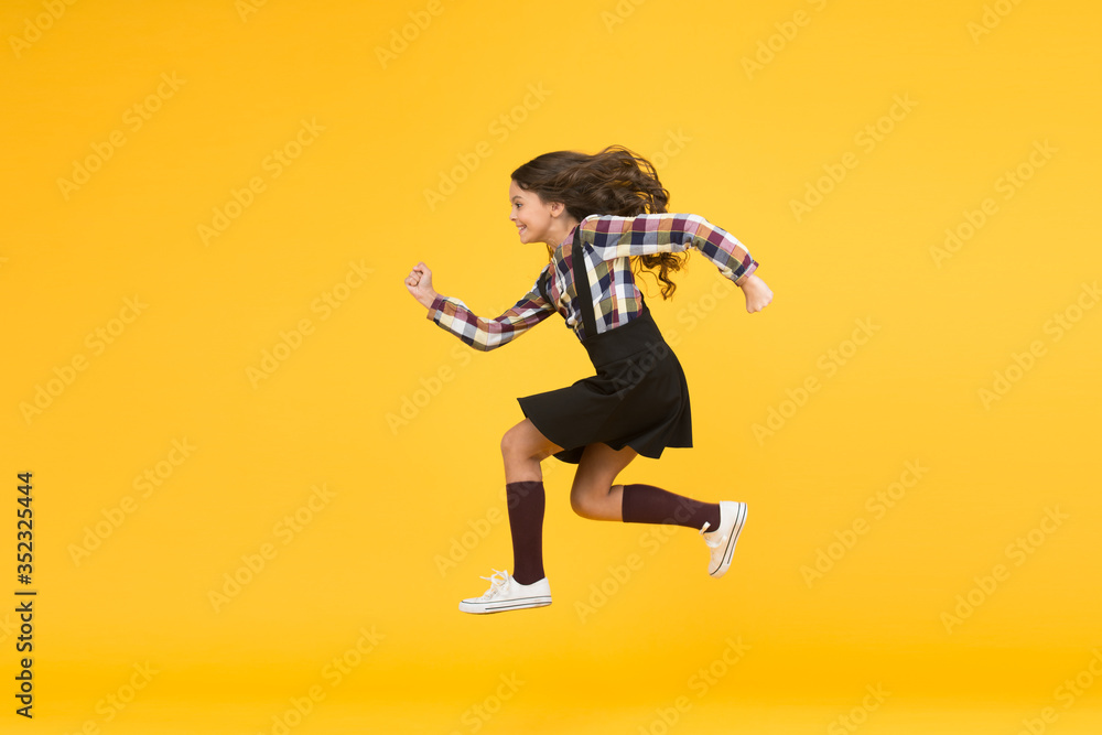 Fototapeta premium Unstoppable future. Happy girl in midair yellow background. Energetic child run to school. Pursuing future goal. Dynamic movement. Childhood and growing up. I will change the future, copy space