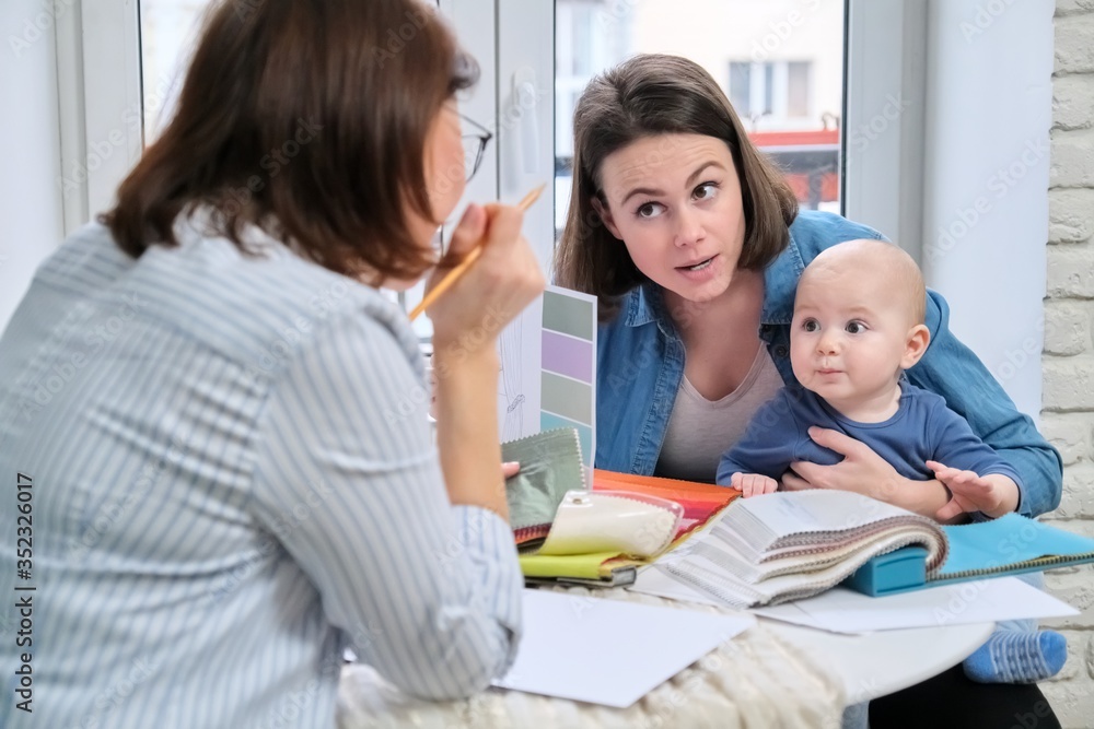 Women interior designer and client with baby choosing fabrics and materials Women interior designer and client with baby choosing fabrics and materials