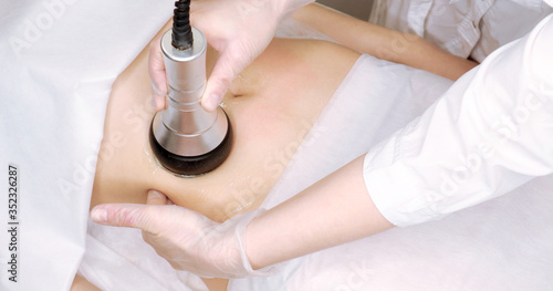 The cavitation procedure closeup. Beautician apparatus for cavitation on the woman's stomach. The concept of skin care face and body