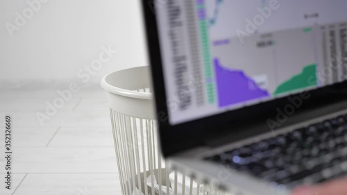 Close-up throwing laptop to the trash bin. The concept of getting rid of gadgets and electronics.