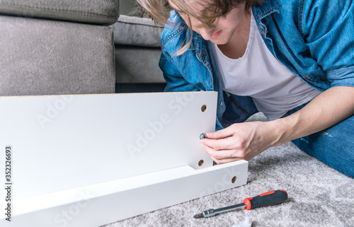 Concentrated young man assembling new furniture for home