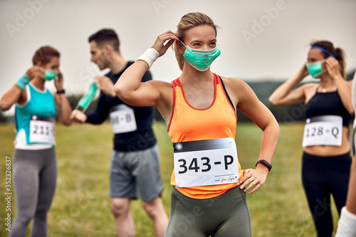 Athletic woman putting on face mask while participating in marathon race.