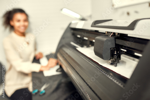 Lets print it. Young woman sitting by computer monitor and sending chosen file to printing machine while printing advertisement sticker with text or picture for a T-shirt