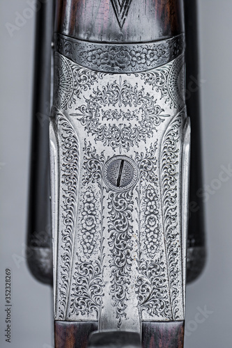 Photo Close up shot of a generic traditional shotgun (commonly used in countryside game sports) featuring the ornate engraved scroll work on the metal