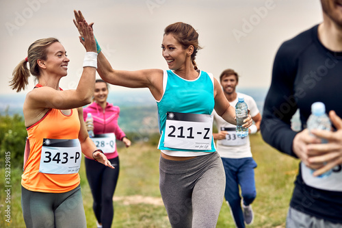 Happy marathon runners giving high-five to each other during the race in nature. photo