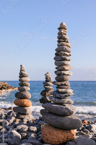 Pyramids built of stones by the sea. Stones of different sizes and keep the balance. Pyramids stand against the blue sky.