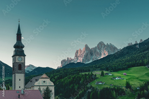 Beautiful view of church in Italian village San Pietro in Dolomites Alps at sunrise. Val di Funes, South Tyrol, Italy