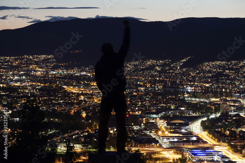 Man Celebrating Success with Hand reised up on Bright City View at Night. photo