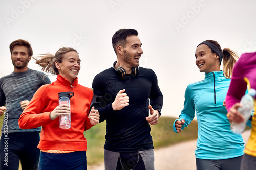 Canvas Print Group of athletic friends talking while jogging in nature.