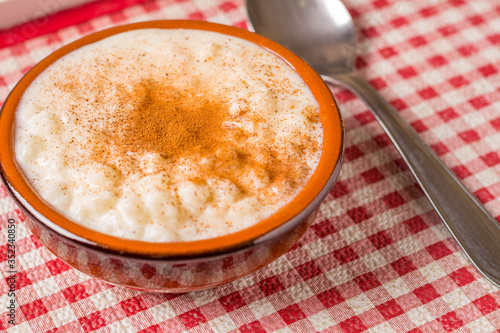 White corn cooked with milk known as canjica, canjicão or mungunza, in a rustic bowl on wooden table. Typical dish of Brazilian Party called Festa Junina.