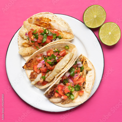 Mexican fish tacos also called Baja with fresh sauce on pink background