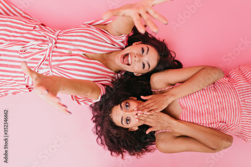 Fotografie Girlfriends with dark curly hair are having fun at their pajama party
