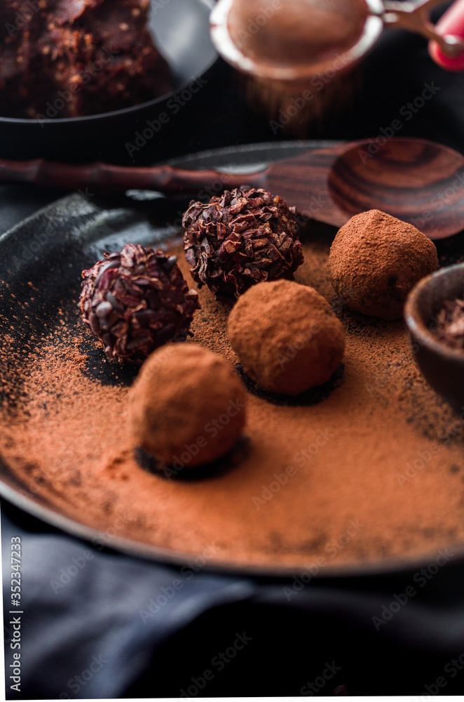 Date energy ball with cocoa on a black dish and cocoa nibs