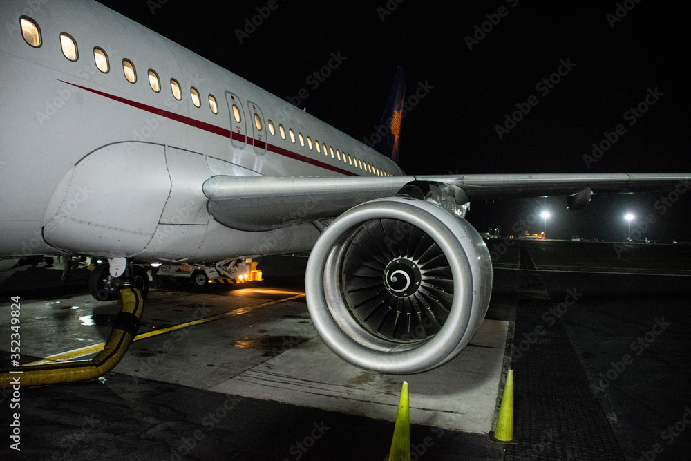 Fototapeta premium Airplane turbine at Cartagena airport, Colombia. Fossil fuel airplane exterior night activity. Transport affected by Covid19.