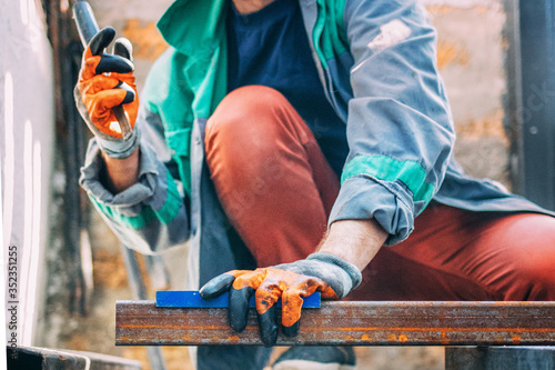 a man measures metal construction with a ruler.