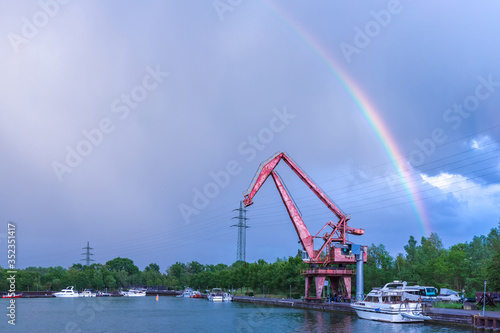 beautiful rainbow after rain in the sky above the river and the old crane