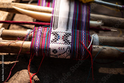 The Peruvian indigenous weaving loom with handcrafts on it with cultural symbols and animal patterns.   photo